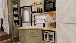 A compact kitchen with a microwave, oven, and built-in shelves. - The Pendle-Tin (Pendleton)