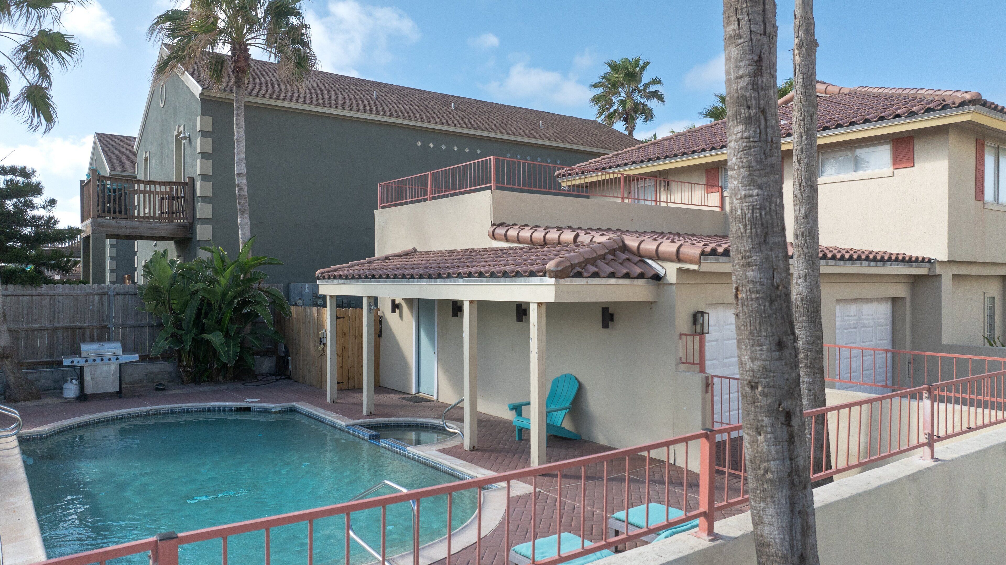 A two-story house with a swimming pool, a covered patio, and a fenced backyard.