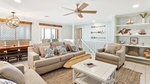 A spacious living room with a large sofa, a coffee table, and a ceiling fan. - Spacious Beachside Home with Private Pool! Dog-Friendly & Directly Across from Beach! (South Padre Island)