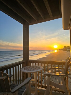A wooden deck with a table and chairs overlooking a beach at sunset. - Beach Views For Miles! Sand & Sea- First floor! (North Topsail Beach)