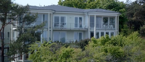 A multi-story residential building with balconies, surrounded by dense greenery.