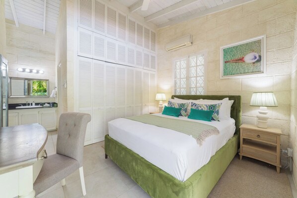 Une chambre à coucher comprenant un lit, une table de chevet, une chaise, ainsi qu’une salle de bain avec un lavabo et un miroir.