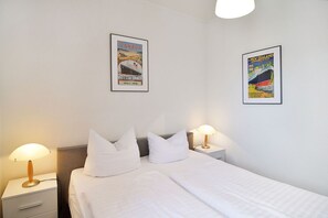 A hotel room with a bed, two bedside tables, and two wall-mounted lamps. There are two framed posters on the wall. - Villa Hamburg Appartement 07 - Villa Hamburg (Heringsdorf)