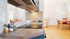 Une cuisine moderne dotée d’un îlot central, d’un four encastré et d’un coin repas avec une table et des chaises.