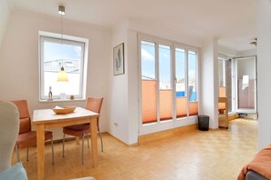 Ein heller Raum mit einem Holzespeisetisch, Stühlen und einem Fenster mit Jalousien.