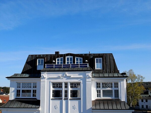 A two-story house with a gabled roof, multiple windows, and a balcony.