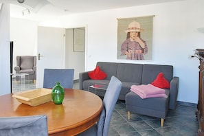 En moderne stue med en grå sofa, røde puder, et træbord og en grøn vase.