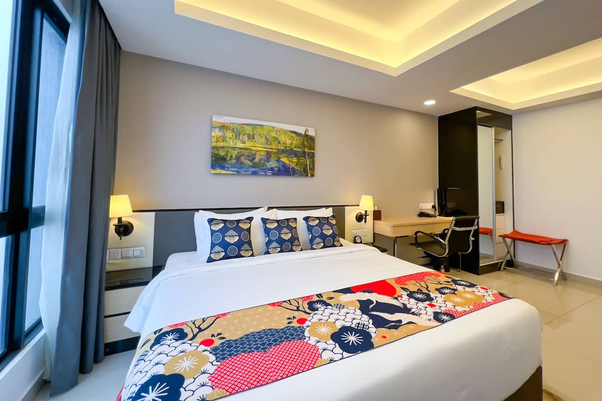 Une chambre d’hôtel moderne avec un grand lit, un bureau, une chaise et un tableau au mur.