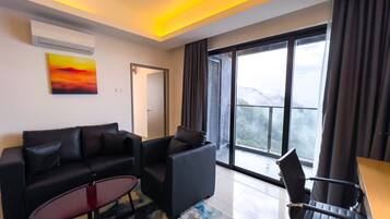 A modern living room with a sofa, a coffee table, and a chair. There is a large window with a view of a mountainous landscape.