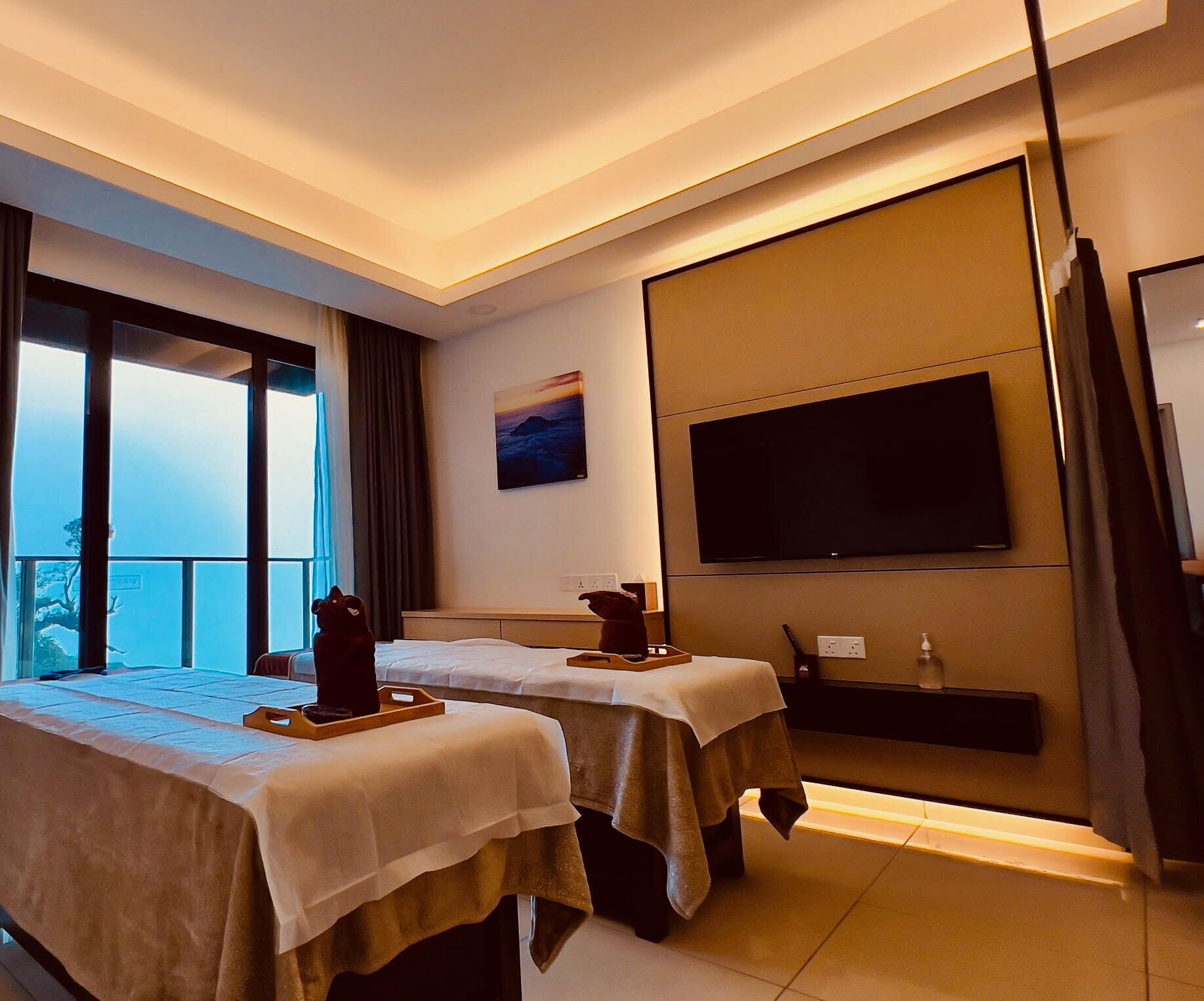 Ein Hotelzimmer mit zwei Betten, einem Fernseher und einem Balkon mit Blick.
