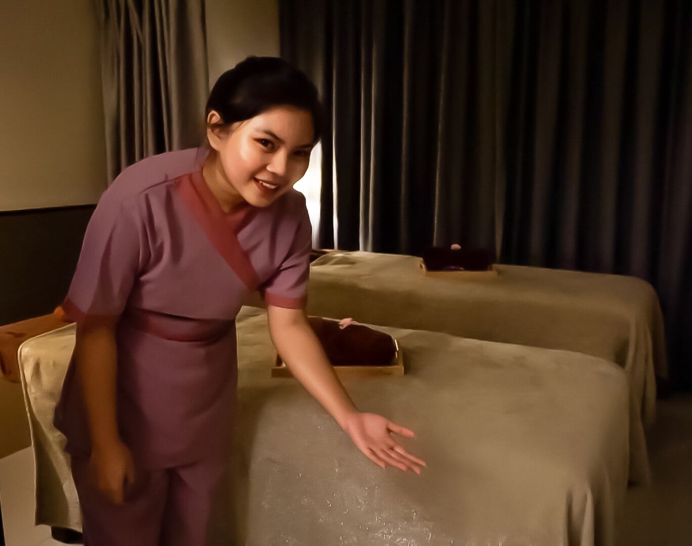 A hotel room with two beds, a nightstand, and a small table.