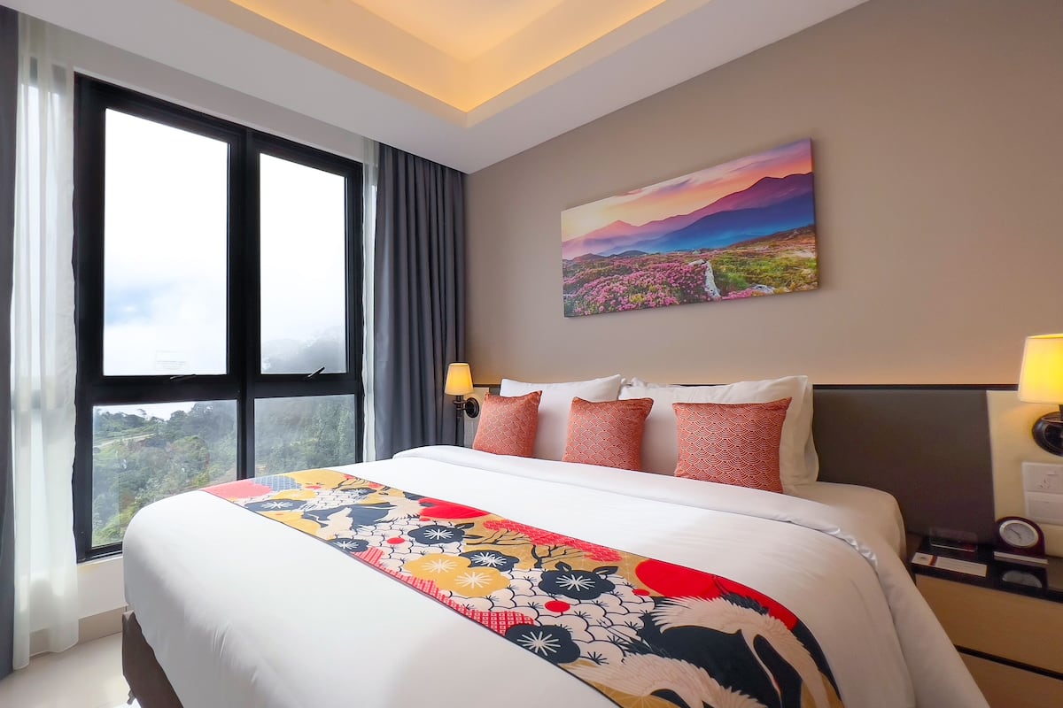 Une chambre d’hôtel avec un grand lit, un tableau au mur et une vue sur l’extérieur par la fenêtre.