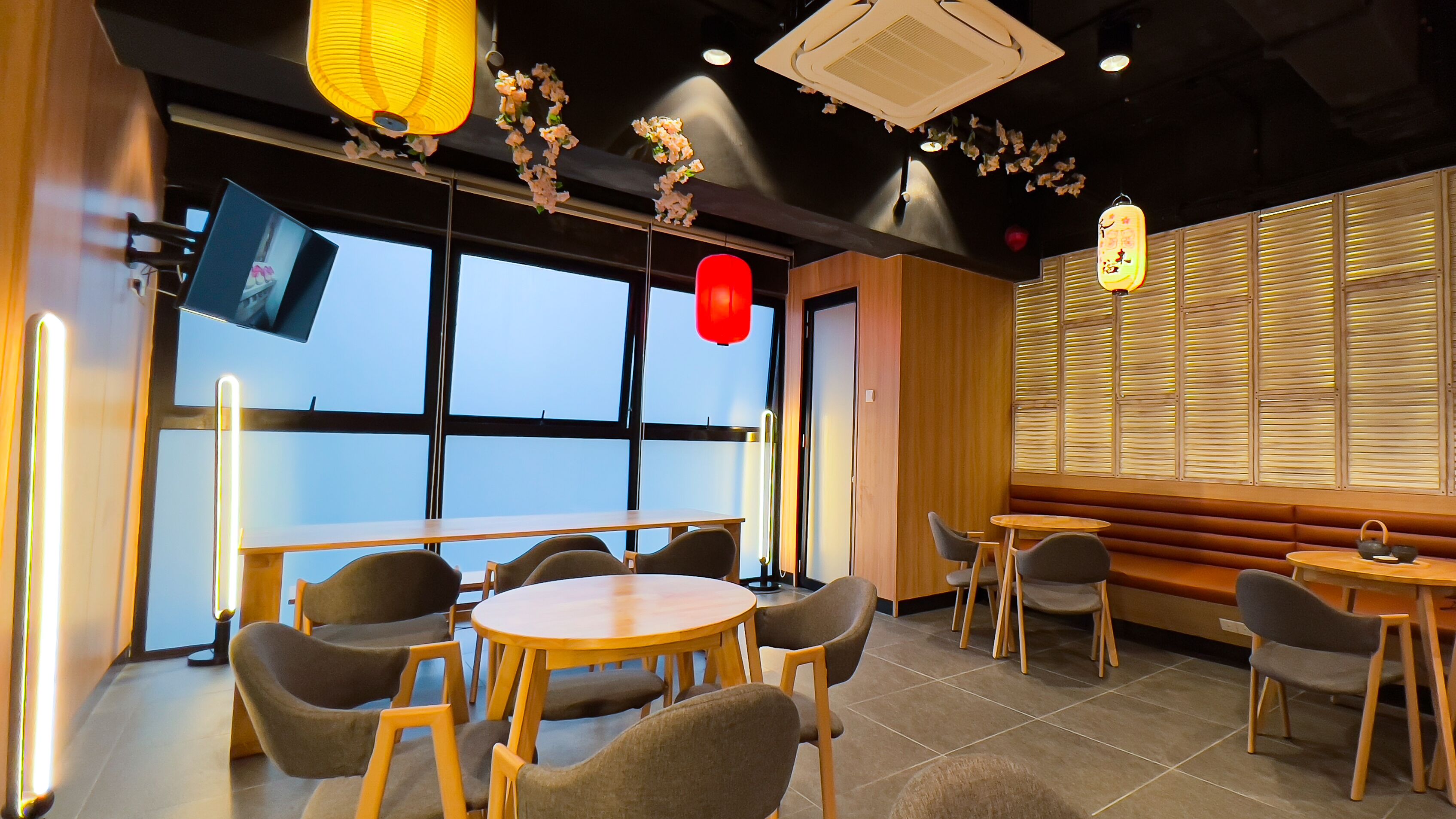 A modern restaurant with round tables and chairs, large windows, and decorative hanging elements.