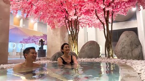 Een warmwaterbronnengebied met kersenbloesems, grote rotsen en een modern interieur.