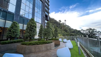 Un edificio moderno con grandes ventanales, rodeado de zonas verdes cuidadas y espacios de estar al aire libre.