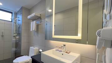 A modern bathroom with a glass shower enclosure, a white sink with a mirror above it, and a hairdryer on the right.