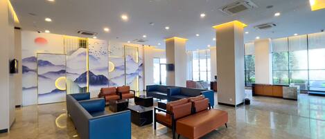 A spacious lobby with seating areas, a large wall mural, and a reception desk.