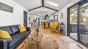 Een moderne woonkamer met een zwarte leren bank, een houten salontafel en een gele fauteuil.