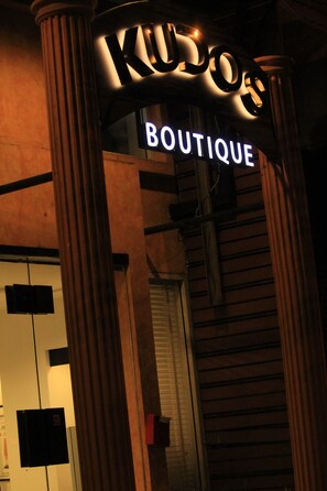A storefront with a sign that reads "KUDOS BOUTIQUE" illuminated in neon lights. - Kudos Boutique Hotel (Pattaya)
