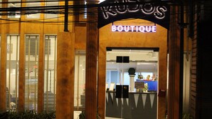 A boutique hotel entrance with a neon sign, large columns, and a reception desk. - Kudos Boutique Hotel (Pattaya)