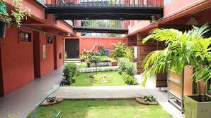 A courtyard with a small garden, a fire extinguisher, and a hose. - Kudos Boutique Hotel (Pattaya)