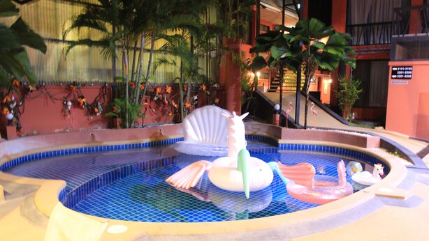 A swimming pool with a decorative fountain and a small island with a statue. - Kudos Boutique Hotel (Pattaya)