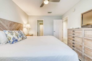 Ein Schlafzimmer mit einem großen Bett, einem Deckenventilator, einem Schminktisch und einem Fernseher.