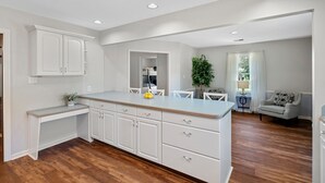 Una cocina amplia con armarios blancos, encimera de madera y un comedor con mesa y sillas.