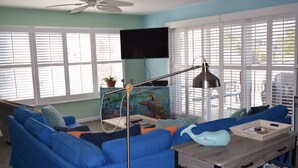 A living room with a blue sofa, a wooden coffee table, and a television mounted on the wall. - Dewey Beach Ocean Block Condo Elevator Parking Sleeps 10 (Dewey Beach)
