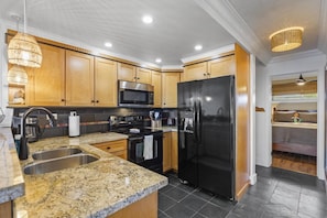 Modern kitchen with stainless steel appliances, granite countertop, and wooden cabinets.