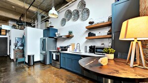 Een moderne keuken met blauwe kastjes, roestvrijstalen apparatuur en decoratieve wandkunst.