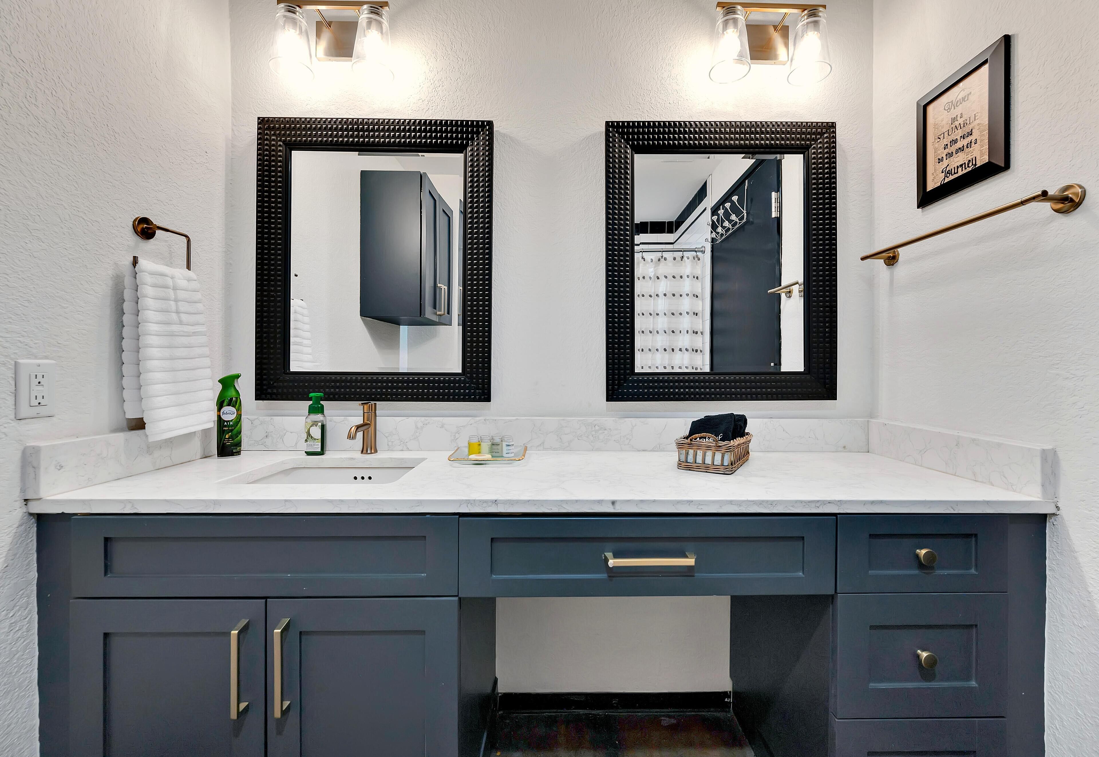 Baño con dos lavamanos, muebles de color azul oscuro y encimera blanca.