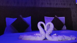 Una stanza con un letto, cuscini e un asciugamano disposti a forma di cuore.