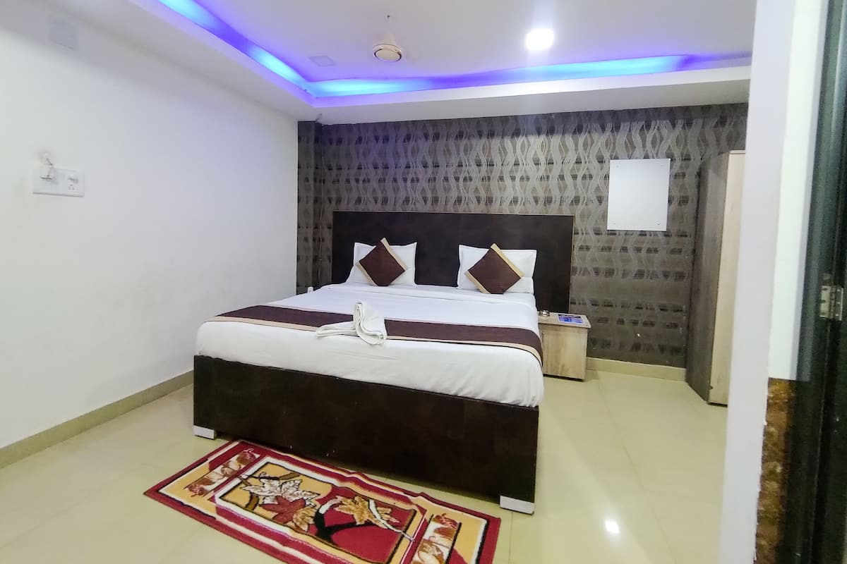 A neatly made bed with a headboard, a bedside table, and a patterned wall.