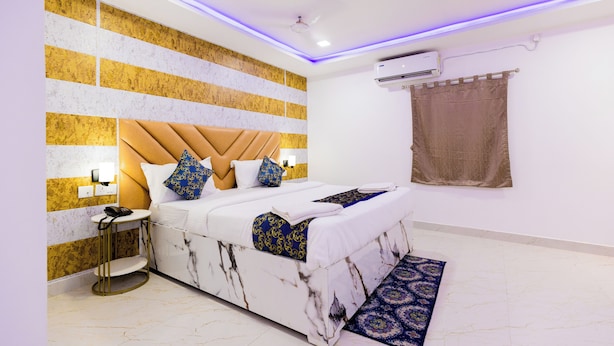 Una camera da letto moderna con un letto in marmo, una testiera, un comodino, un tavolino notturno, un condizionatore d'aria a parete e un tappeto decorato.
