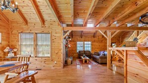 A wooden cabin interior with a dining area, living room, and a fireplace. - Starry Mountain Night | Seasonal Private Pool + Pool Table, Kid`s Playset (Stanton)