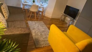 Un salon avec un canapé, une table à manger et des chaises, ainsi qu’un téléviseur.