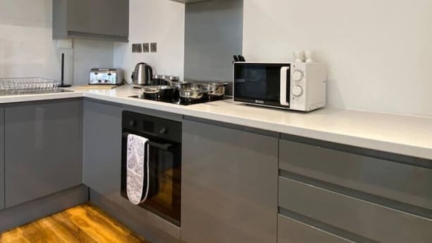 Une cuisine moderne avec des meubles gris, un four à micro-ondes, une bouilloire et un grille-pain.
