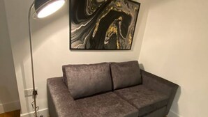 A room with a gray sofa, a black floor lamp, a marble artwork, and a gray rug.