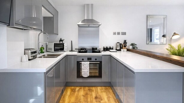 A modern kitchen with a central island, built-in oven, and stainless steel appliances. - Spacious 2BR Bradford Home for 6 (Bedford)