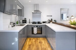 A modern kitchen with a central island, built-in oven, and stainless steel appliances.