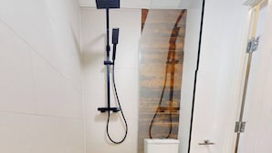 A modern bathroom with a shower, toilet, and a glass partition. - Spacious 2BR Bradford Home for 6 (Bedford)