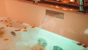 Ein Badezimmer mit einer Badewanne, einem Wasserhahn und einer kleinen digitalen Anzeige.