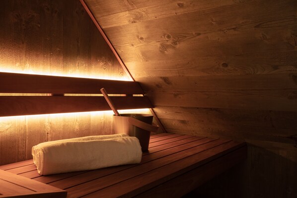 Un banco de madera con una toalla y una jarra, probablemente para una sauna o baño de vapor.