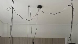 Eine moderne Küche mit weißen Arbeitsplatten, einem Edelstahl-Kühlschrank und Pendelleuchten mit freiliegenden Kabeln.
