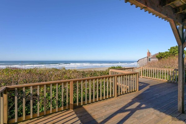A wooden deck with a railing overlooking a beach.
