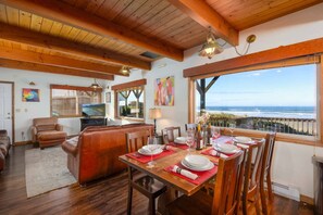 A dining area with a table set for six, overlooking the ocean.