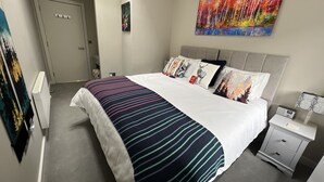 Ein Hotelzimmer mit einem großen Bett, einem Nachttisch, einem Heizkörper und einem Gemälde an der Wand.