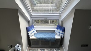 Ein Zimmer mit einer Dachfensterkuppel, einer Bank mit Kissen, einem Heizkörper und einem Teppich.