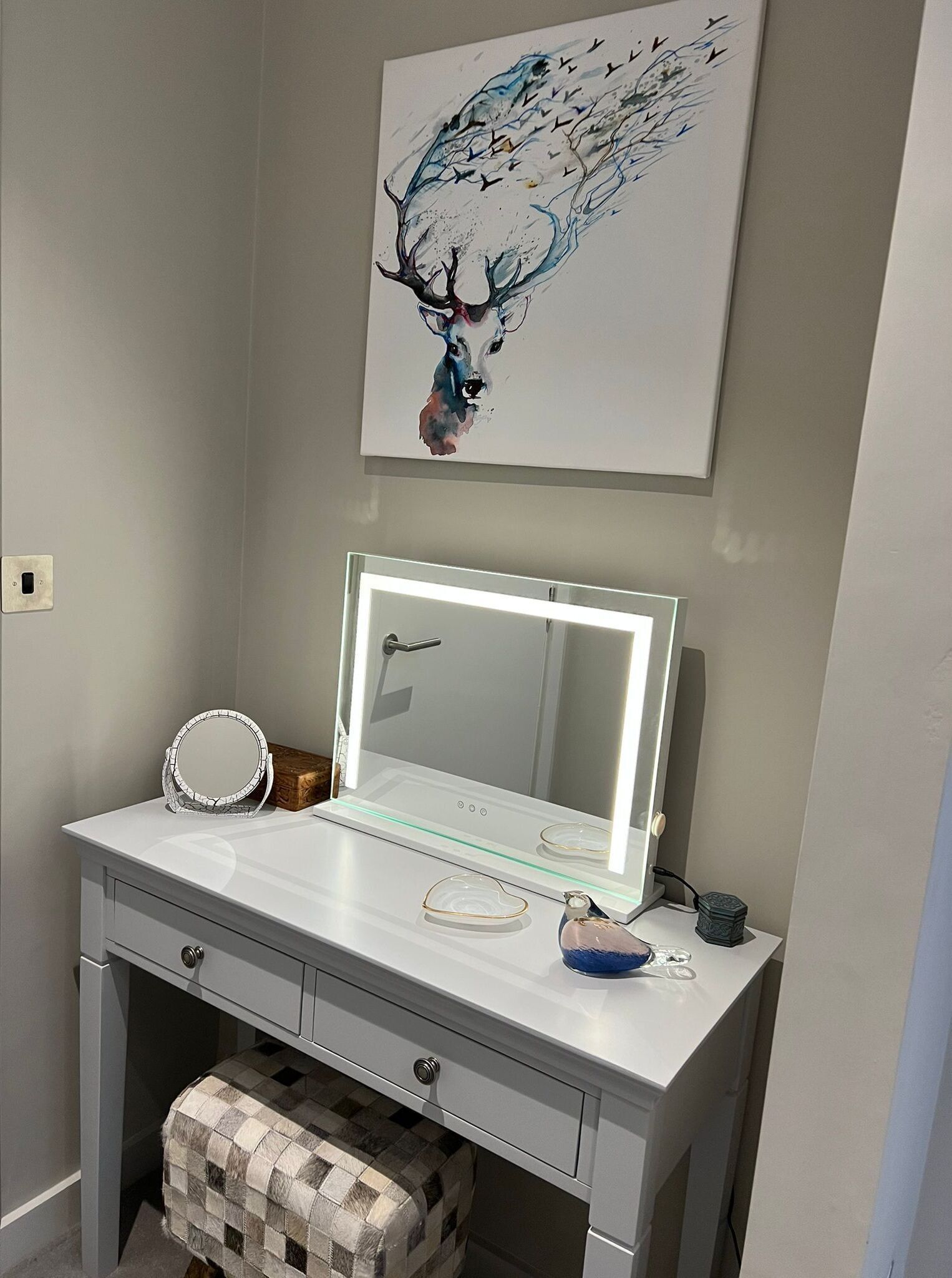 Un meuble-lavabo de salle de bain avec un miroir, des luminaires et un élément décoratif placé au-dessus.